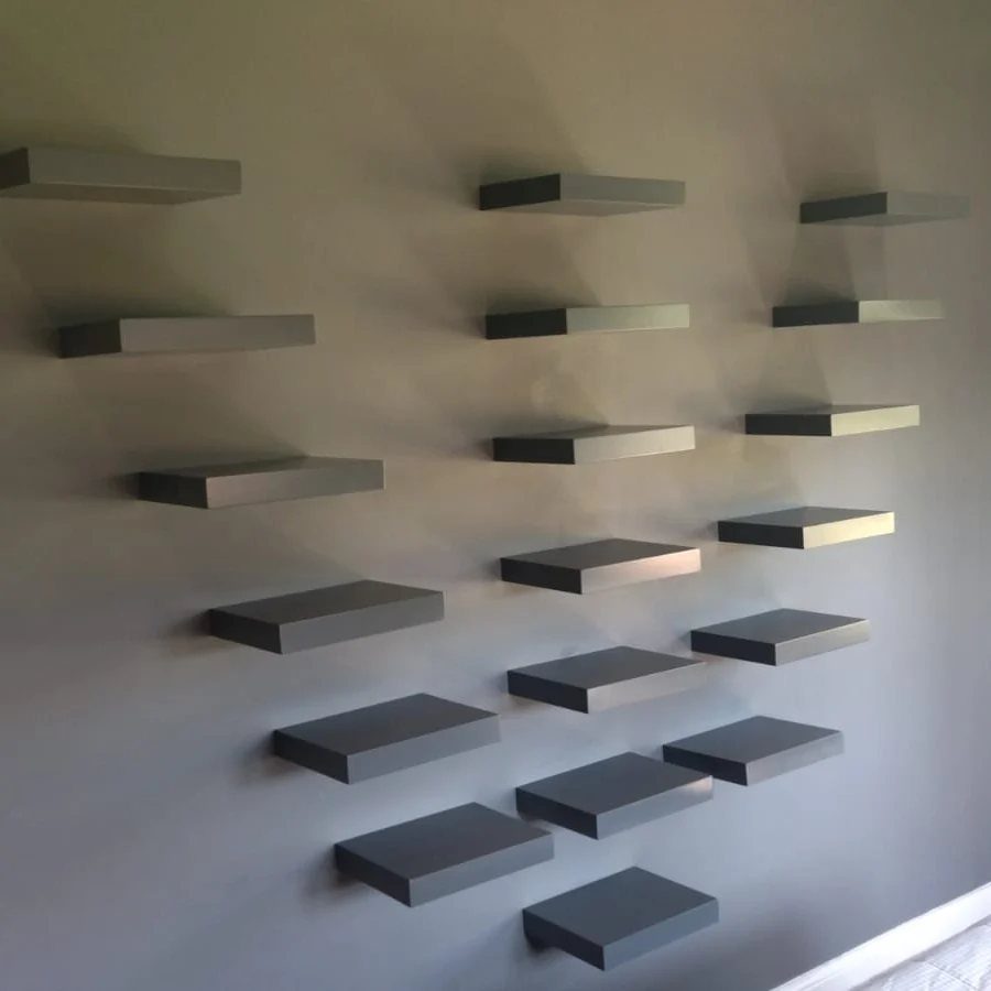 Grey rectangular floating shelves mounted on a wall in a staggered pattern.