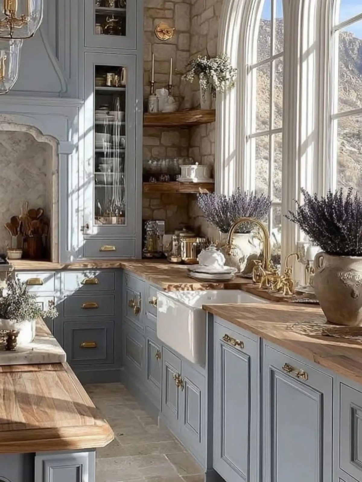 Light blue farmhouse kitchen cabinets with wooden countertops and a white farmhouse sink near arched windows.