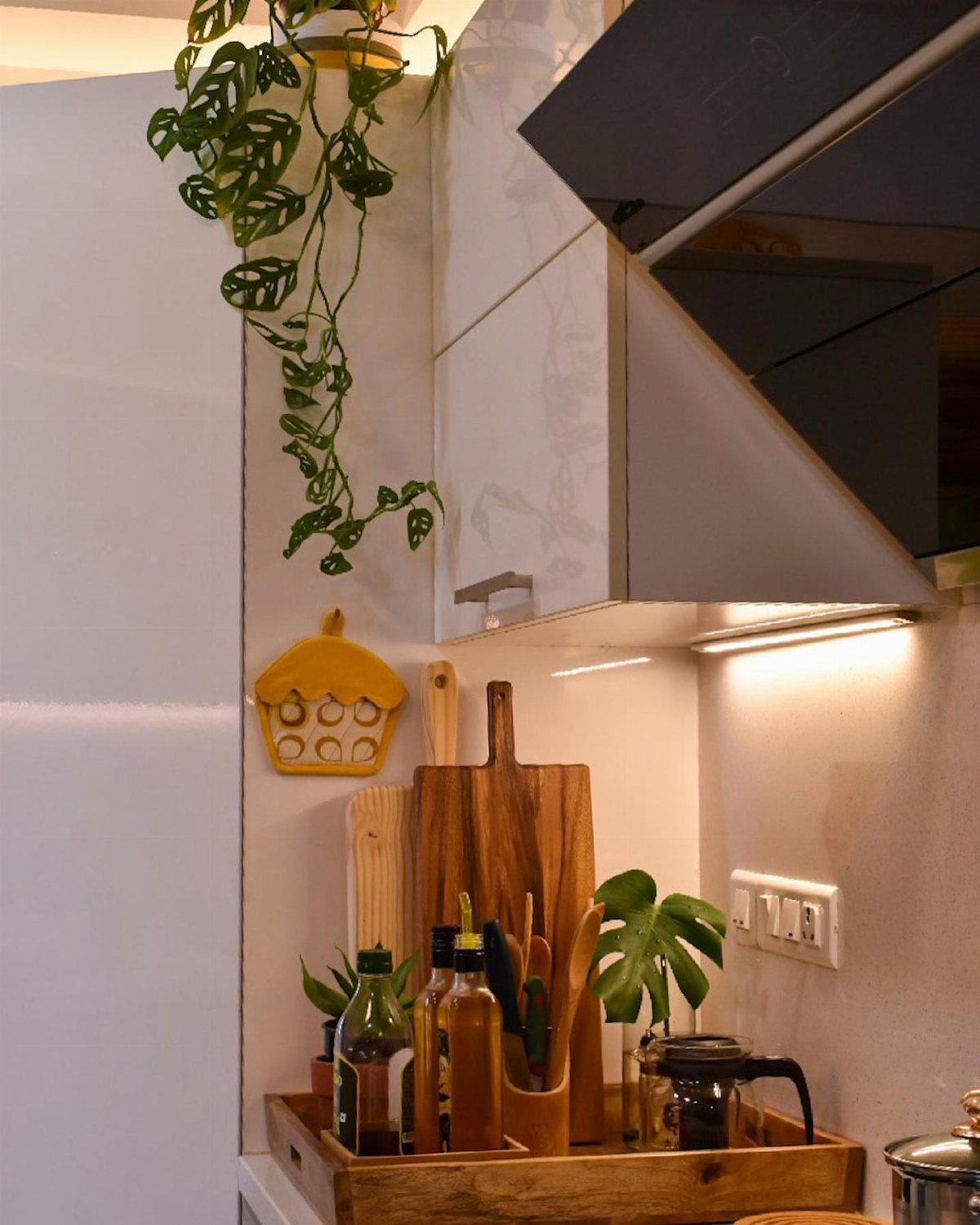 Wooden tray on a kitchen counter holding oil bottles and cooking utensils.