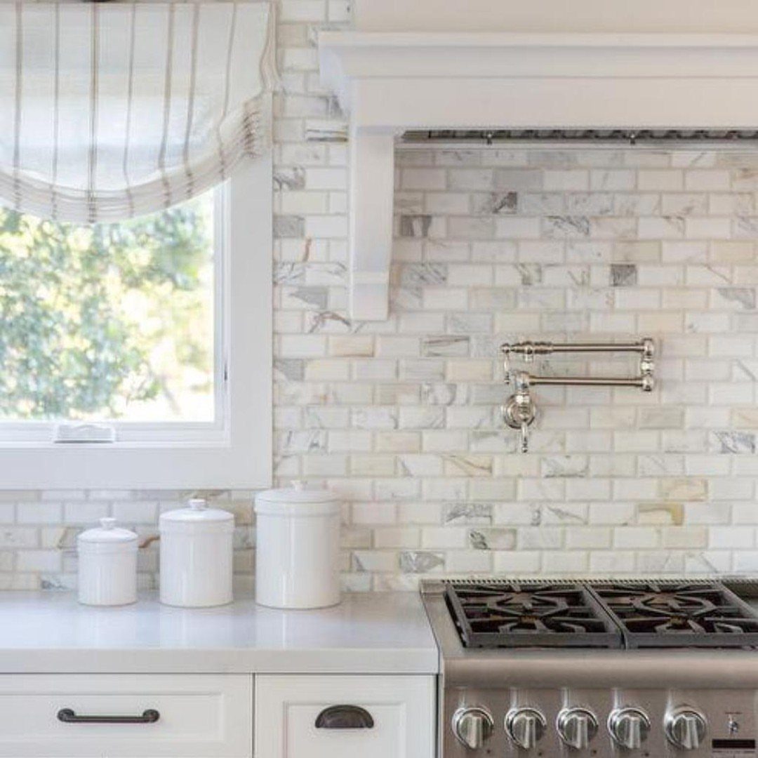 Marble subway tiles in white and grey tones covering a kitchen backsplash wall.